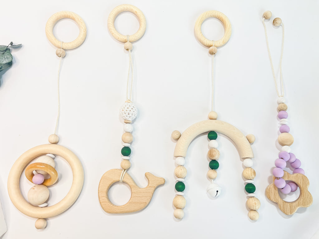 Vier Designs von Holzspielzeug-Anhängern für Spielbogen, Baby Gym oder Maxi Cosi – nachhaltige Materialien, BPA-frei und sicher für Babys