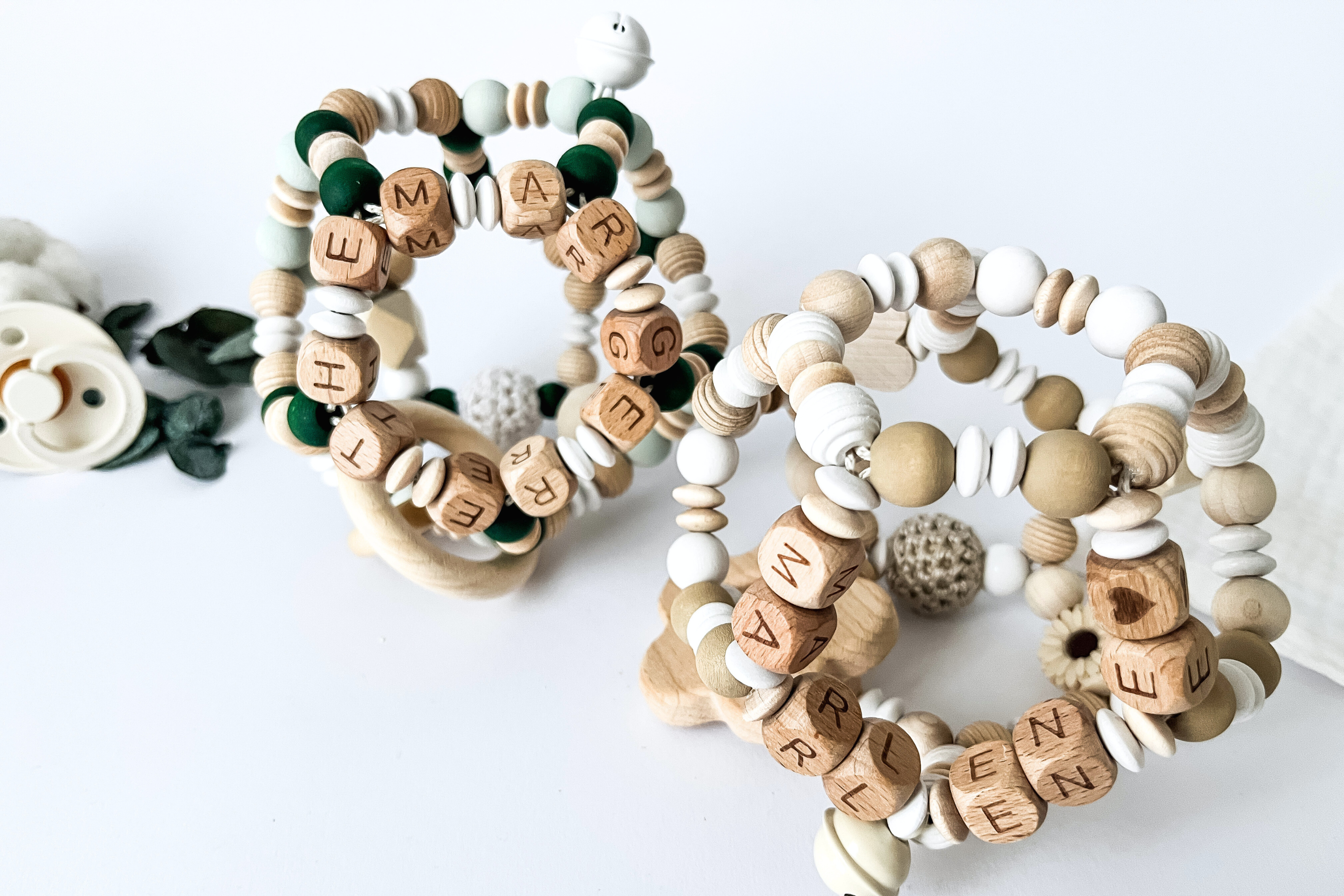 Zwei personalisierte Motorikbälle aus Holz mit Namen, handgefertigt in den Farbkombinationen Grün „Forest Flow“ und Beige „Beige Bliss“, liebevoll gestaltet für Babys.